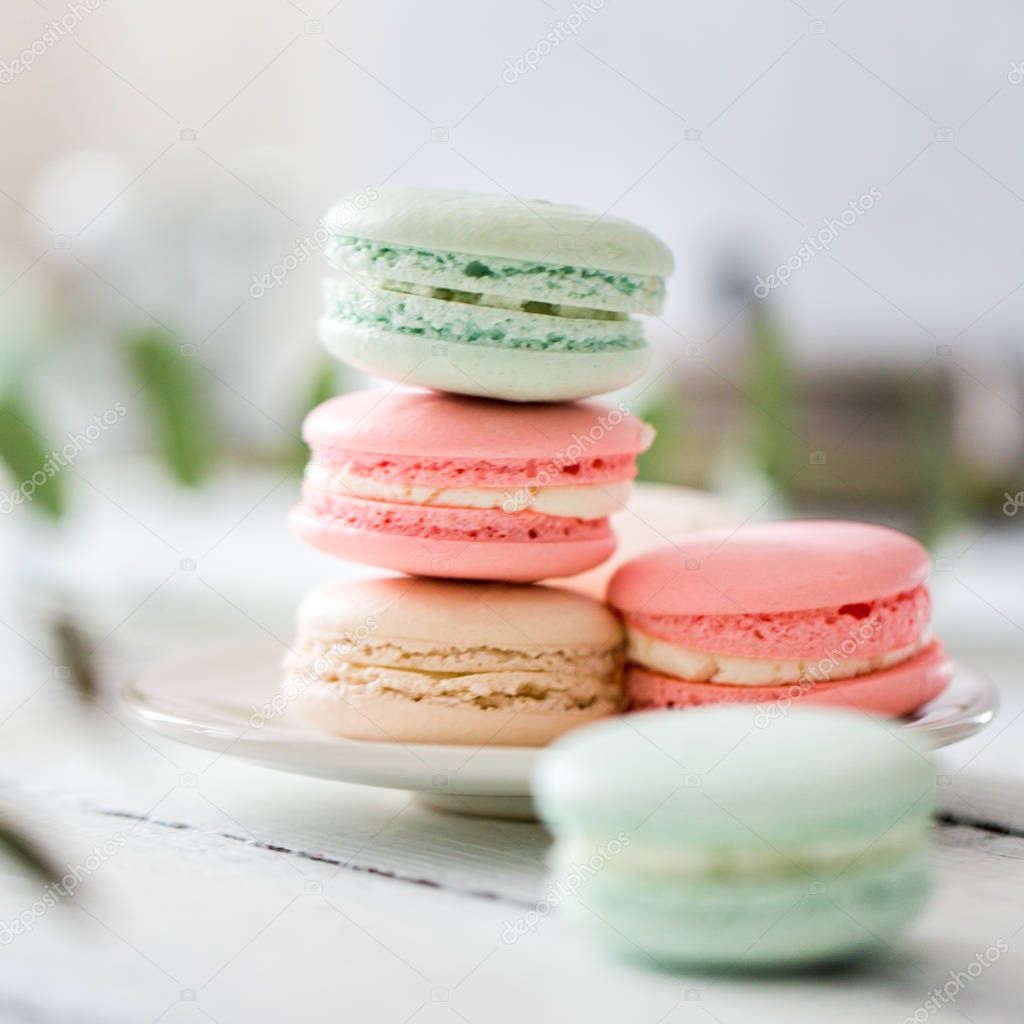 Colorful French or Italian macarons stack on white plate put on wood table with copy space for background. Dessert for served with afternoon tea or coffee break.Beautiful meal background with blank.