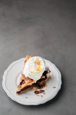 Gri hafif beton zemin üzerine beyaz vintage tabakta vanilyalı dondurma ile vişneli pasta bir parça. Uzay kopyalayın. Metin için boş alanı gösterme.