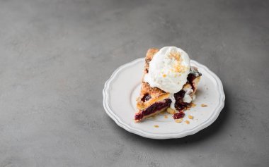 Gri hafif beton zemin üzerine beyaz vintage tabakta vanilyalı dondurma ile vişneli pasta bir parça. Uzay kopyalayın. Metin için boş alanı gösterme.