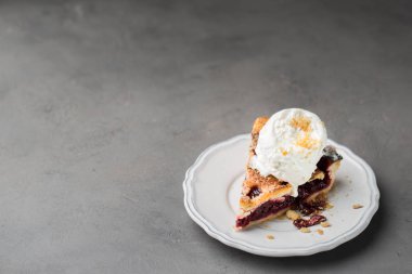 Gri hafif beton zemin üzerine beyaz vintage tabakta vanilyalı dondurma ile vişneli pasta bir parça. Uzay kopyalayın. Metin için boş alanı gösterme.