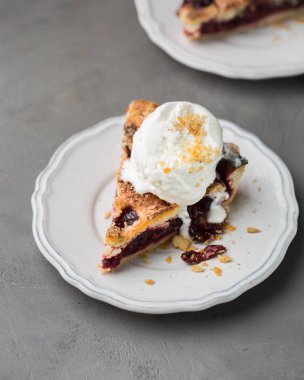 Gri hafif beton zemin üzerine beyaz vintage tabakta vanilyalı dondurma ile vişneli pasta bir parça. Uzay kopyalayın. Metin için boş alanı gösterme.