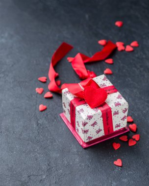 Kırmızı kurdeleli hediye kutusu ve siyah beton zeminde şeker kalpler. Güzel Sevgililer Günü. Romantik bir ruh hali..) 