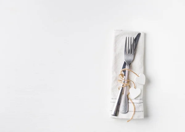 Valentines day (or wedding) meal background with hearts, fork, knife, white napkin. Romantic holiday table setting. Beautiful background with blank. Restaurant concept. Flat lay