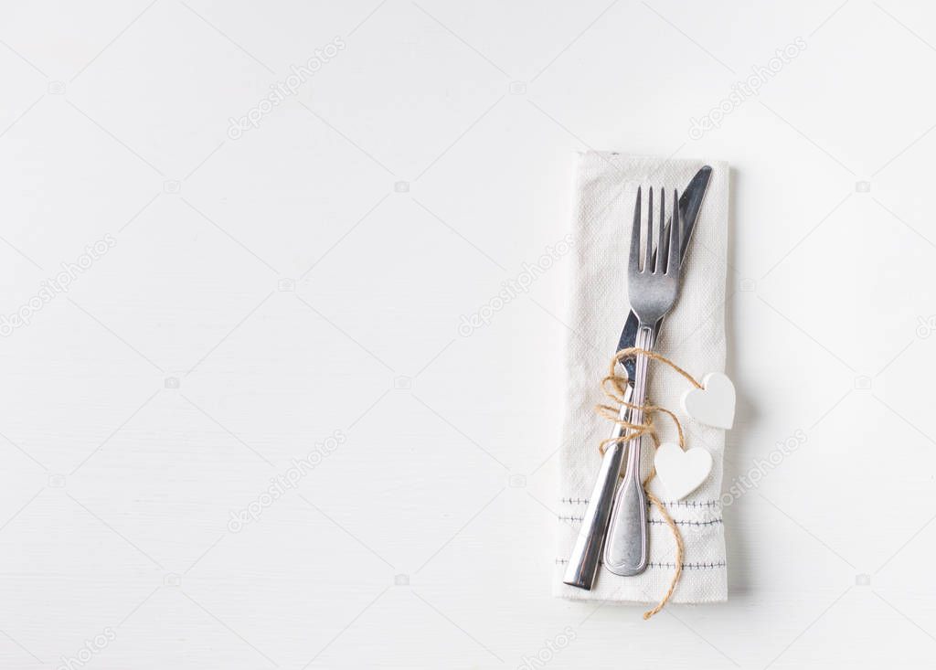 Valentines day (or wedding) meal background with hearts, fork, knife, white napkin. Romantic holiday table setting. Beautiful background with blank. Restaurant concept. Flat lay