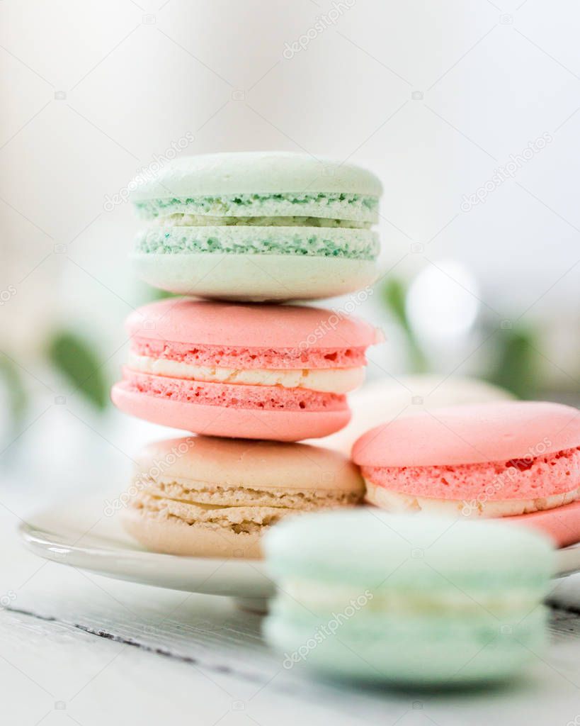 Colorful French or Italian macarons stack on white plate put on wood table with copy space for background. Dessert for served with afternoon tea or coffee break.Beautiful meal background with blank.