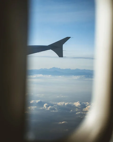 Vista da cabine do avião. Através da janela. Fotografia de avião acima de nuvens e montanhas . — Fotografia de Stock