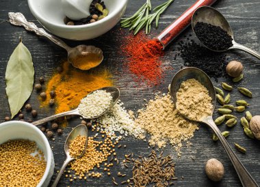 Siyah bir arka plan üzerine dağılmış renkli baharatlar