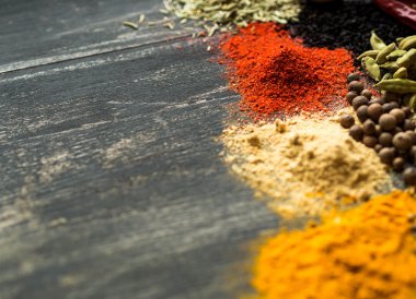 Siyah bir arka plan üzerine dağılmış renkli baharatlar