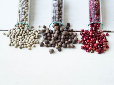 Beyaz ahşap arka plan üzerinde cam şişelerde biber farklı türler