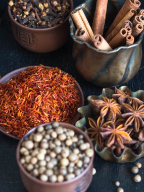 Karanlık bir arka plan üzerine bir kase içinde çeşitli baharatlar