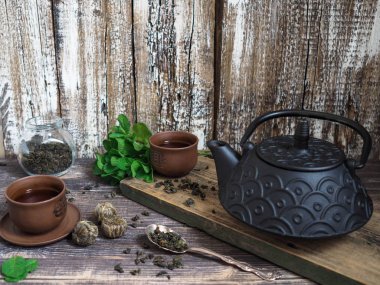 Yeşil çay ve nane bir fincan çay yanında bir delikanlı ile siyah bir çaydanlık 