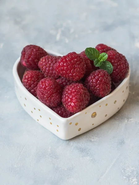 Ripe large raspberry and a sprig of mint in a bowl in the shape of a heart — Stock Photo, Image