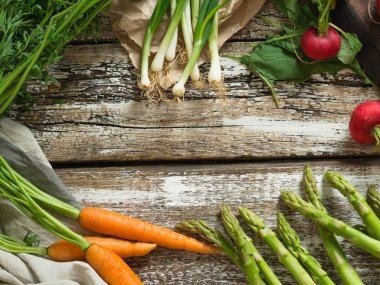 Eski bir ahşap zemin üzerinde çerçeve bahar sebzeler. 