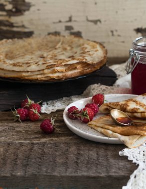 Ahududu reçeli ve kara tahta üzerinde taze çilek ile kızarmış krep yığını. Rus tarzı.