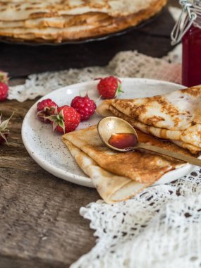 Ahududu reçeli ve kara tahta üzerinde taze çilek ile kızarmış krep yığını. Rus tarzı.