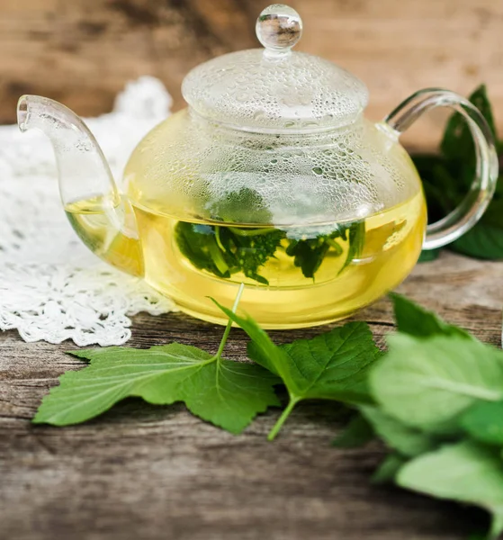 Rustik ahşap bir masa üzerinde bitki çayı ile cam çaydanlık