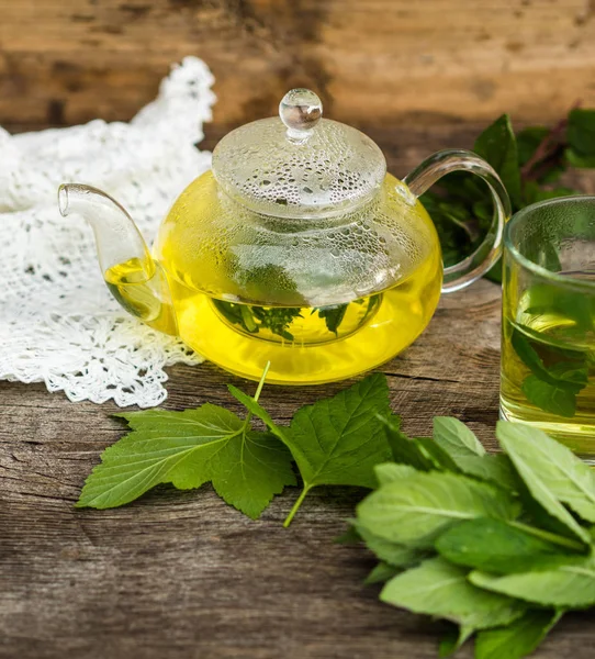 Rustik ahşap bir masa üzerinde bitki çayı ile cam çaydanlık