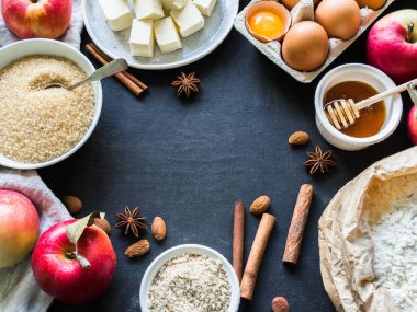 maddeler bir çerçeve şeklinde elmalı turta için karanlık bir arka plan üzerinde ayarlayın. Elma, un, şeker kamışı, badem unu, bal, baharatlar, yumurta ve tereyağı. gıda kavramı.