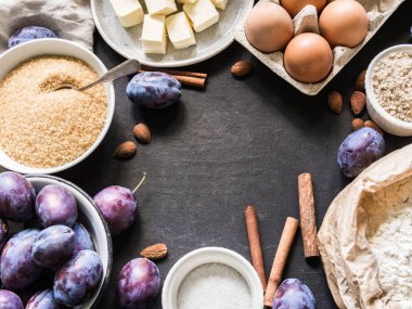 birtakım karanlık bir arka plan üzerine bir kare şeklinde erikli kek için malzemeler. Erik, şeker kamışı, badem unu, baharat, yumurta ve tereyağı. gıda kavramı.