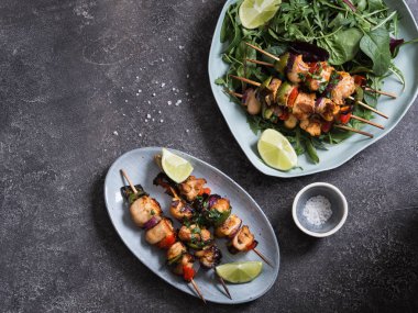 Tavuk şiş üzerinde gri arka plan üzerinde oval tabak ve taze salata tabağı ile karışık yeşillik şiş üzerinde tavuk