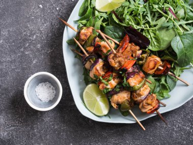 Taze salata tabağı ile tavuk şiş ve kireç gri bir arka plan üzerinde mavi tabak karışık yeşillik ile