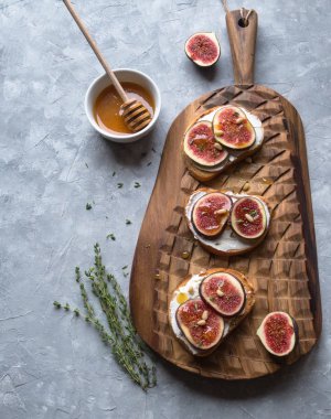 Ricotta ve incir tatlım kekik ve çam fıstığı gri bir arka plan üzerinde bir gemide ile üç tost