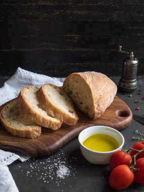 ekmek dilimleri bir dal kiraz domates, zeytinyağı, baharat ve tuz yanındaki bir gemide dilimlenmiş. Koyu arka plan