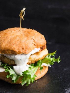 Ev yapımı balık burger bir şeyl siyah tahta üzerinde