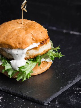 Ev yapımı balık burger bir şeyl siyah tahta üzerinde