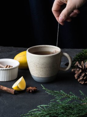 Çay limon ve bal karanlık bir arka plan üzerinde bir kupa. El ile çay poşeti