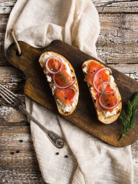 Kaba ahşap arka planda, eski tahtada füme somon ve krem peynirli iki sandviç. Üst görünüm