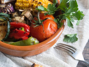 Seramik bir kabın içinde çeşitli ızgara sebze. Domates, kabak, soğan, Mısır, mantar, kırmızı biber