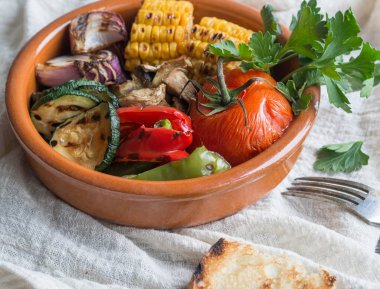 Seramik bir kabın içinde çeşitli ızgara sebze. Domates, kabak, soğan, Mısır, mantar, kırmızı biber