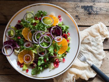 Marul salata mandalina, nar ve eski bir ahşap masa üzerinde kırmızı soğan ile