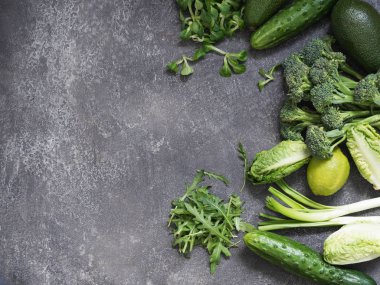 Taze yeşil sebze çeşitli rustik gri arka plan üzerinde. Marul, roka, Mısır marul, yeşil gem marul, avokado, kireç, brokoli, salatalık.