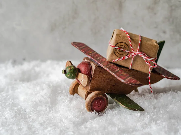 Composición navideña con un avión vintage de madera que lleva un regalo navideño — Foto de Stock
