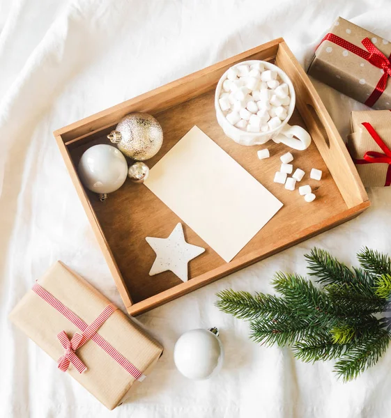 Papperskort för brev i träbricka, mugg med varm dryck och marshmallows och juldekoration. Flat lay för God Jul eller Gott Nytt År. — Stockfoto