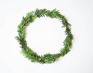 Yuvarlak çerçeveli yeşil, taze ladin dalları beyaz arka planda. Üst görünüm