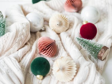 Köknar ağacı ve beyaz örgü arka planında farklı Noel toplarıyla yaratıcı bir Noel kompozisyonu. Üst görünüm