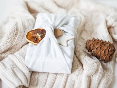 Fabric wrapped gift with paper tag, dry orange slice and ceramic star. Reusable sustainable gift wrapping alternative. clipart