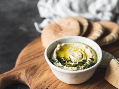 Geleneksel ev yapımı civciv bezelye humusu, zeytin yağı ve ahşap kesme tahtasına sürülmüş kırmızı biber baharatı serpiştirilmiş..