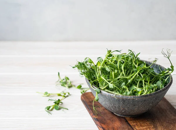 Färska unga gröna ärtor groddar i en skål på ett bord. Kopiera utrymme — Stockfoto