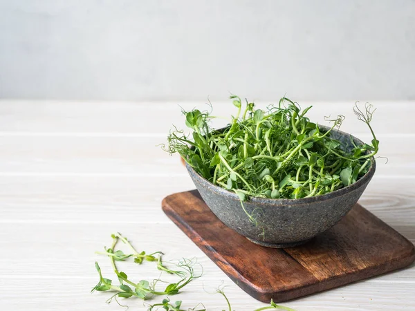 Färska unga gröna ärtor groddar i en skål på ett bord. Kopiera utrymme — Stockfoto