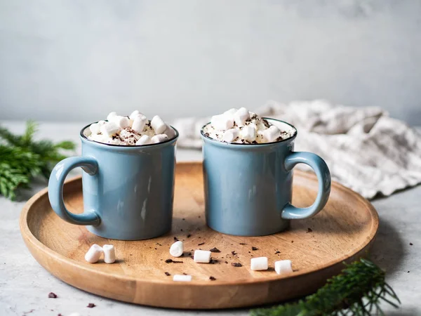 Two blue mugs with hot chocolate, whipped cream, chocolate chips on a wooden tray on gray background. Copy space — Stock Photo, Image