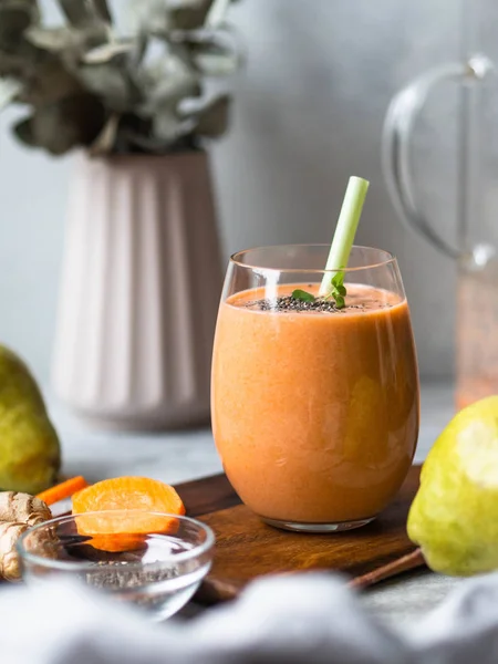 Bir bardak taze, sağlıklı havuç, armut, gri arka planda chia tohumlu zencefilli smoothie.