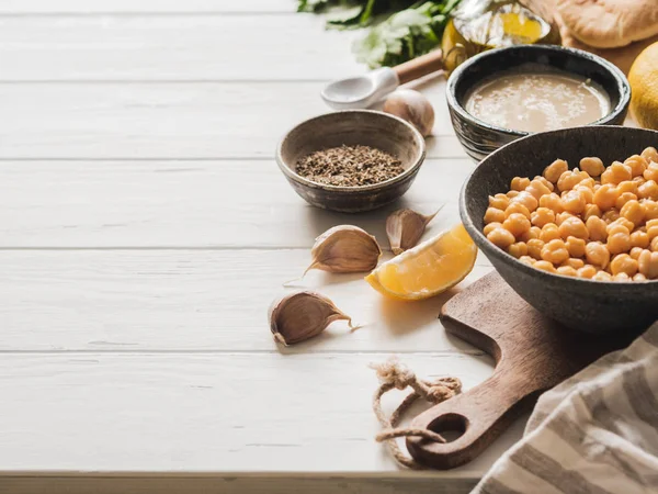 Set de ingredientes para cocinar hummus tradicional casero sobre un fondo de madera blanca. Copiar espacio —  Fotos de Stock