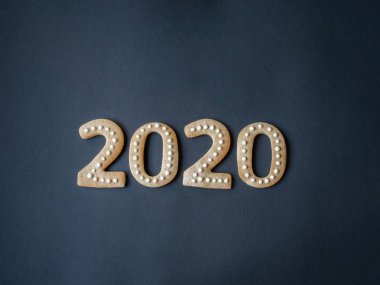Sayılar formunda zencefilli bisküviler ve 2020 yılındaki zencefilli kurabiyeler ve koyu arkaplan. Üst görünüm.