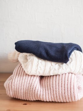 Sıcak örülmüş yün süveter yığını pastel gölgeler ve masaların üzerinde koyu mavi.