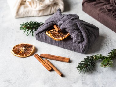 Eco-friendly fabric reusable gifts packaging with fir brunch, cinnamon stick and dry orange slice. Christmas reusable sustainable gift wrapping alternative. Zero waste concept. clipart