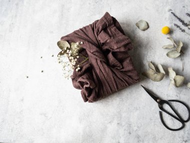 Çevre dostu kumaş yeniden kullanılabilir okaliptüs ve beyaz çiçeklerle birlikte. Romantik sürdürülebilir hediye paketleme alternatifi. Sıfır atık.